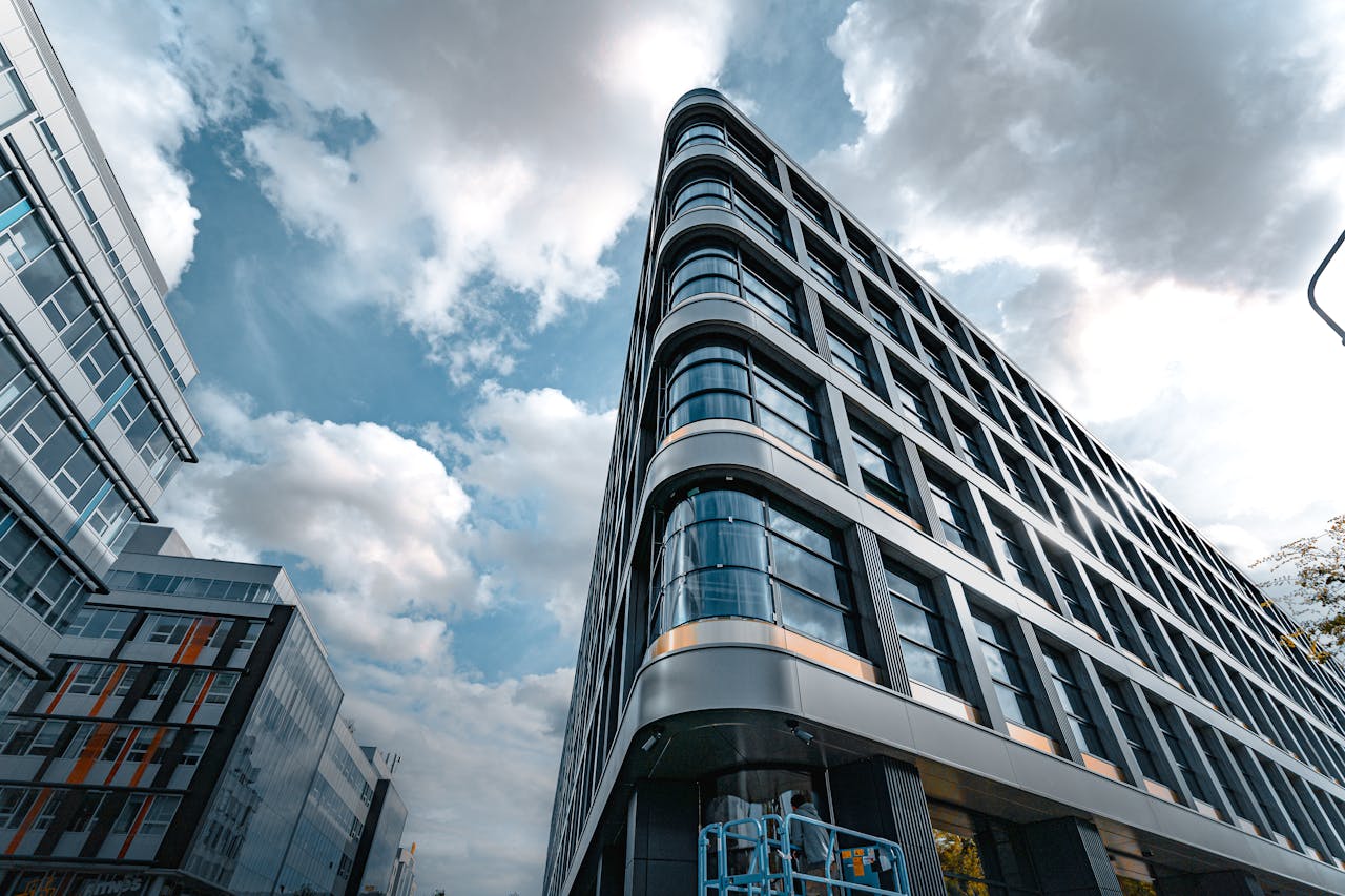 Low angle view of a modern office building with a sleek glass facade against a cloudy sky.